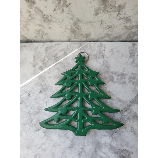 An interesting early 20th century cast iron trivet with a geometric Christmas tree pattern. It has a loop for hanging and...