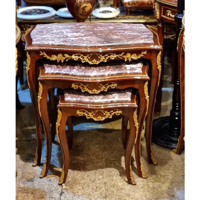 Elegant Rococo style nesting tables featuring a luxurious set of three accent tables topped with sophisticated beige and...
