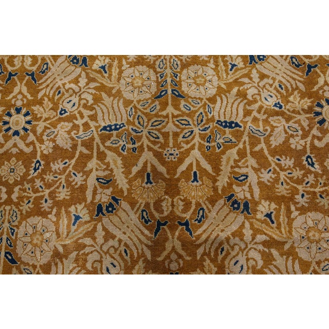 An early 20th century Indian rug, the caramel field with an allover trellis of flowerheads and flowering vines within a...