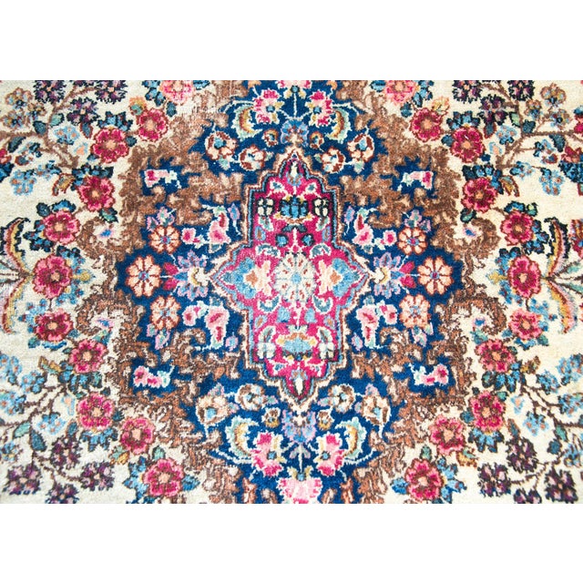 A stunning early 20th century Persian Kirman rug with a central floral medallion with a stepped floral pattern with myriad...