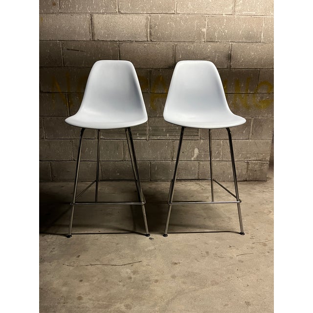 One iconic pair of light gray molded plastic bar stools by Charles & Ray Eames for Herman Miller, 2017. These beautiful...