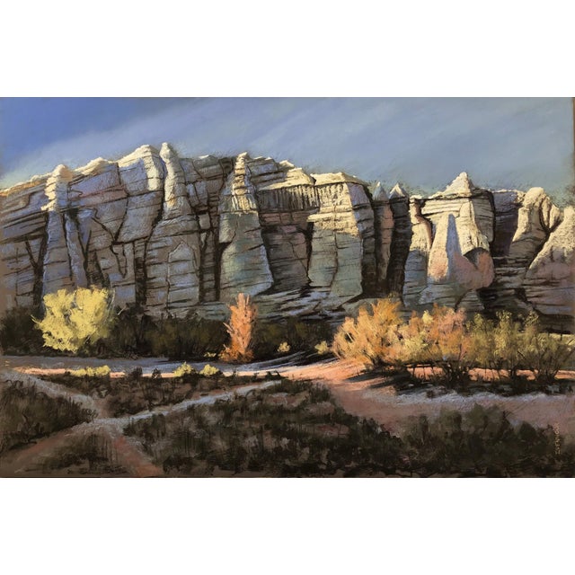 This pastel artwork captures a striking desert landscape, featuring rugged rock formations bathed in warm sunlight. The...