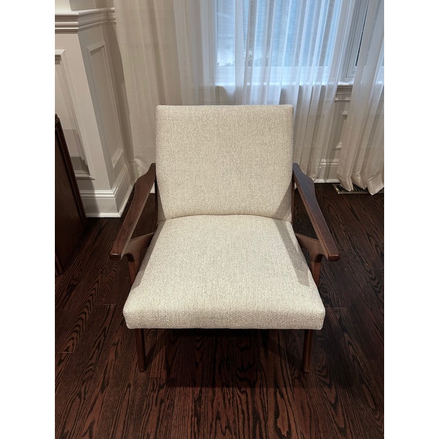 A mid-century-inspired accent chair and matching ottoman from Crate & Barrel's Cavett collection — solid wood frame with...