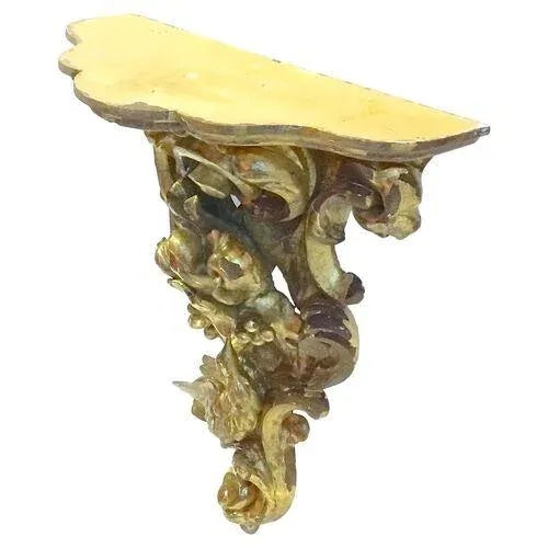 Antique Florentine wall bracket hand-carved with a bird, acanthus leaves, and scrollwork supporting a scalloped top shelf....
