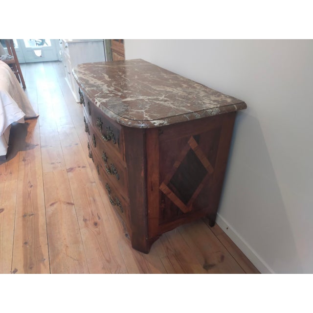 Chest of drawers dating from the mid-18th century. Inlaid with wood. Pink marble top and bronze handles.