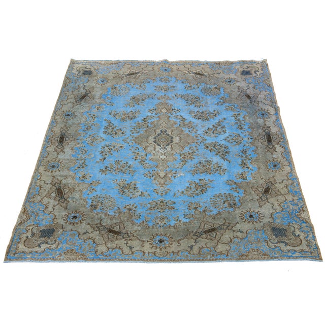 This antique Persian wool rug features a medallion floral design in light blue with beige and brown accents, all hand-...