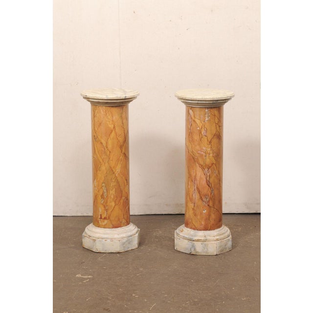 An Italian pair of faux-marbled column pedestals from the mid 20th century. These vintage pedestals from Italy each...