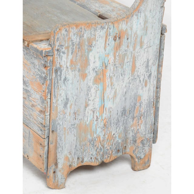 A charming 19th-centry country pine settle bench with old, naturally worn blue surface paint. The bench features and open...