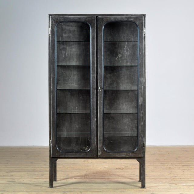 Vintage medicine cabinet from the 1970s, produced in Hungary. The cabinet is made of iron and glass, with the glass held...