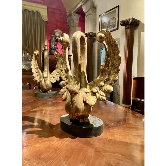 This magnificent pair of hand carved wood and gilt with gold leaves swans sculptures represents an extraordinary example...