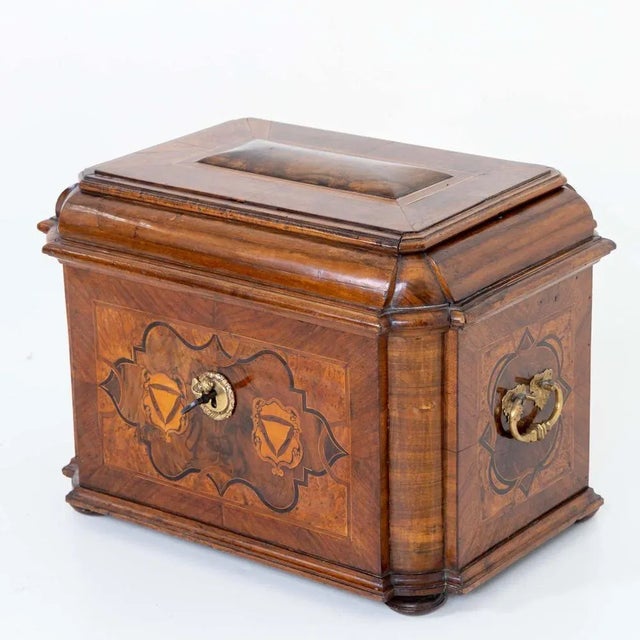 Baroque guild chest with side brass handles and domed lid. The body stands on pressed ball feet, has rounded corners and...