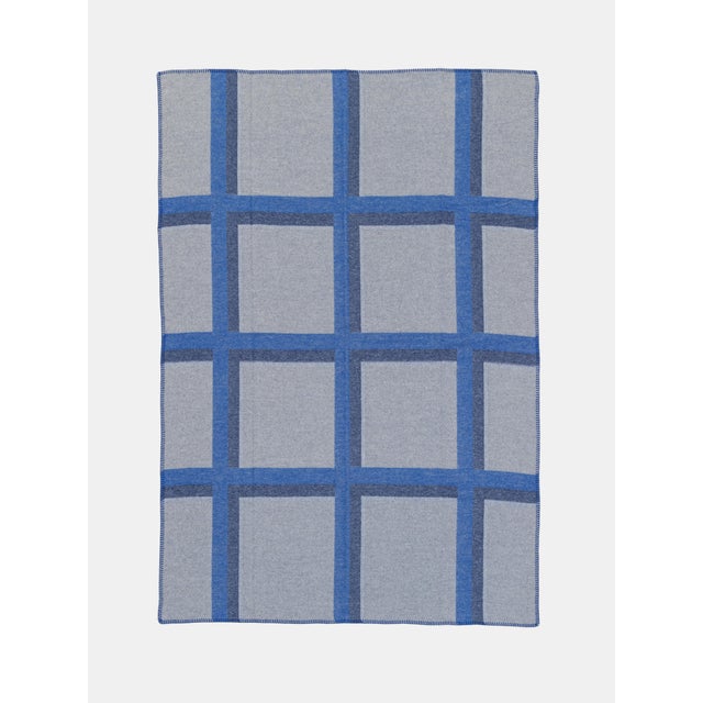 Jacquard throw in merino wool with geometric pattern and blanket stitch finish.