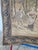 The tapestry depicts an idyllic, forest genre scene in shades of beige and brown. In the foreground there are groups of...