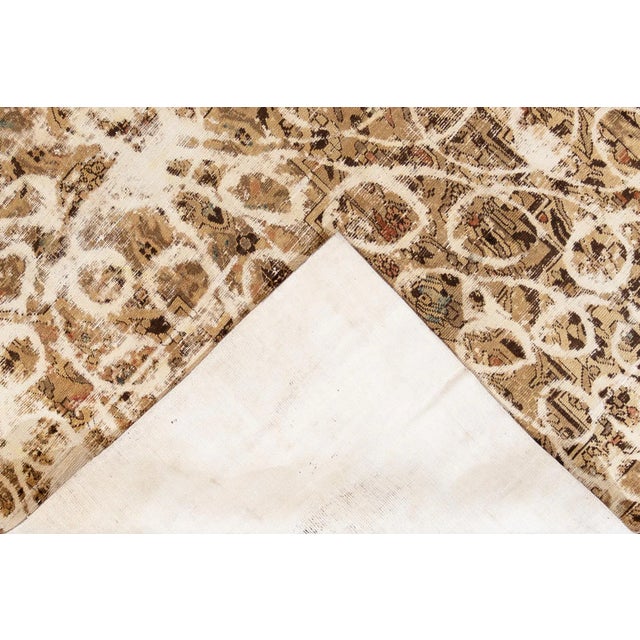 Beautiful hand-knotted vintage wool rug with a tan field. This distressed rug has blue and brown accents featuring an all-...