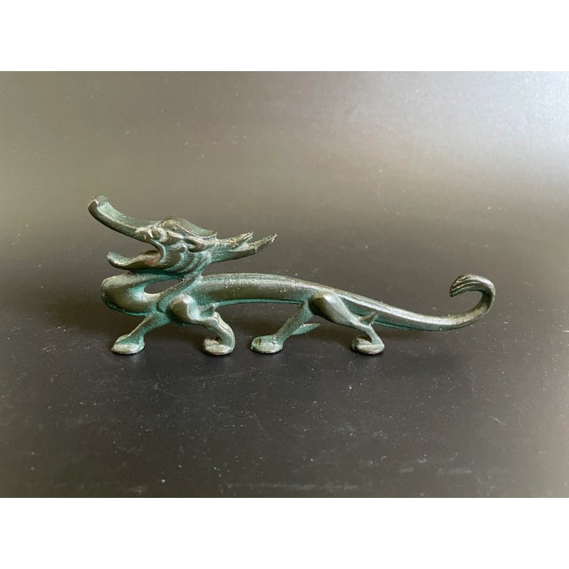 Antique Chinese iron brush rest cast in the form of a crouching dragon. Has a tint of dark green. Its intricate design...