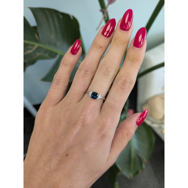 An indicolite tourmaline in a deep ocean blue anchors this solid 14K white gold ring, framed by ten earth-mined diamonds....