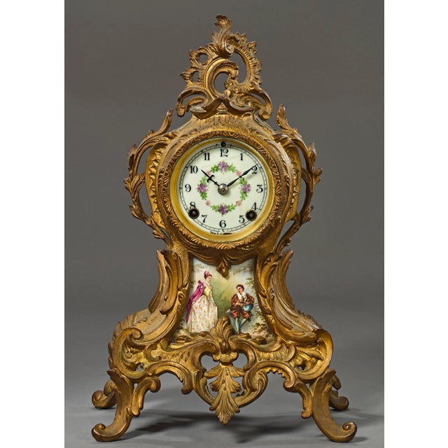 This is a very elegant clock with a porcelain face and a porcelain plaque in the opening below the face with a painted...