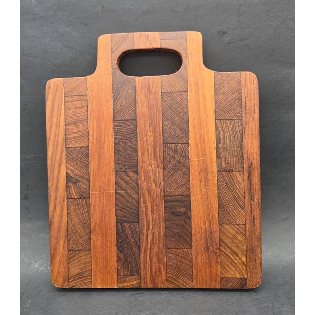 Offered is a handcrafted Teak wood end-grain cutting board featuring an integrated handle cutout and alternating hardwood...