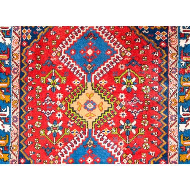 A bold and playful mid-20th century Persian Yallameh rug with three large central diamond medallions surrounded by...