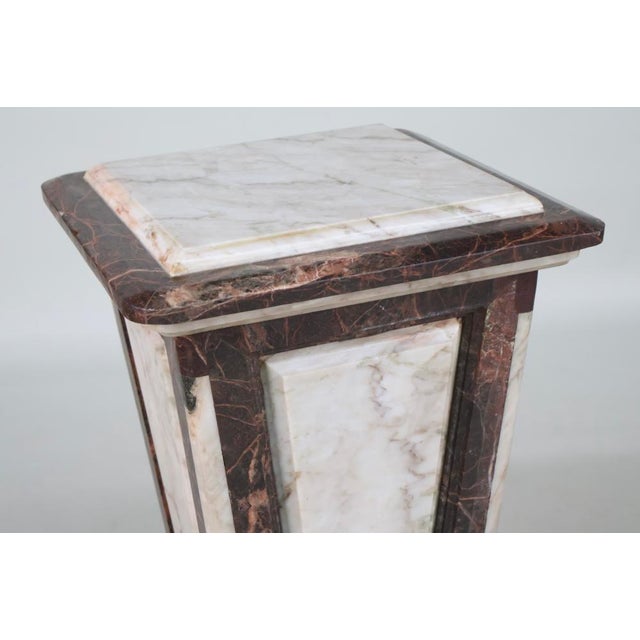 An elegant and substantial pair of early 20th-century neoclassical marble pedestals, or gaines, featuring richly veined...