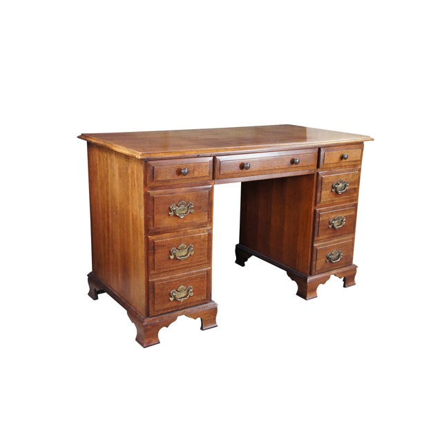 1970s Vintage kneehole writing desk. Made from cherry with colonial style brass hardware. Features seven dovetailed...