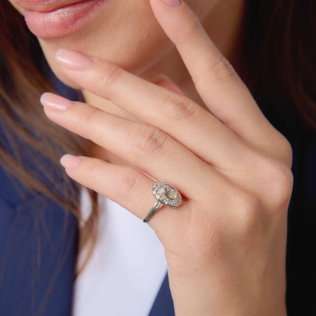 This elegant Art Deco cluster engagement ring showcases a beautifully proportioned 1.02 carat oval diamond, offering a...