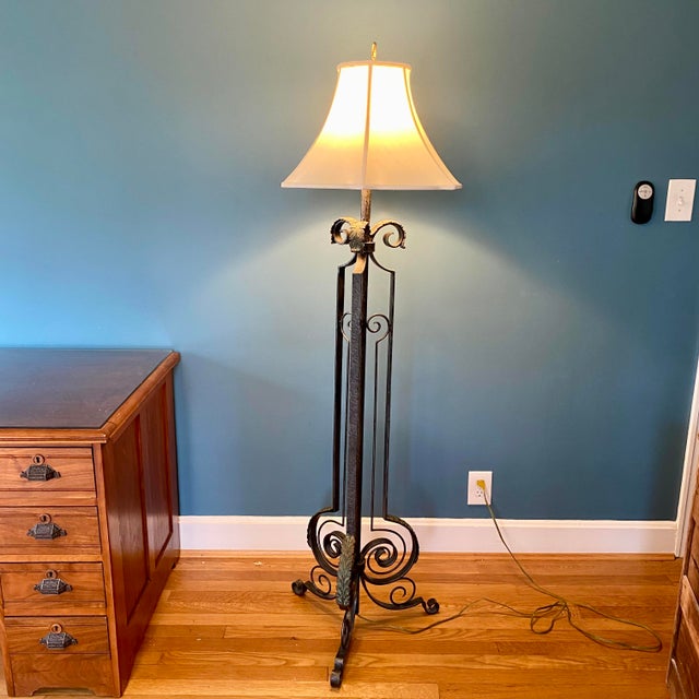 This impressive standing lamp features an off-white bell shade and three scrolled legs adorned with acanthus leaves. The...