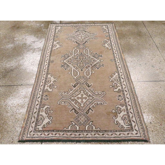 An antique Turkish Oushak accent rug. An open rose ground sets off two styles of Oushak medallions, each based on a...