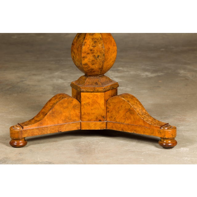 A French Empire period walnut table from the 19th century with circular marble top, pedestal and tripod base. Evoke the...