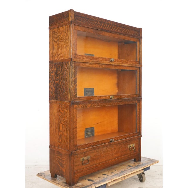 This Globe Wernicke quarter sawn oak piece has three bookcase units with lift up doors and a pull out drawer below. The...