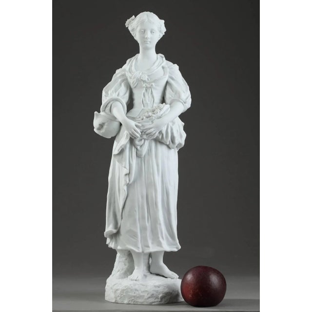 19th century biscuit porcelain figurine featuring a young woman holding a bunch of flowers in her skirt. This figurine is...