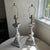 Neutral cream and gray wood lamps feature a chipped irregular paint finish. Tiered painted gray wood bases compliment the...