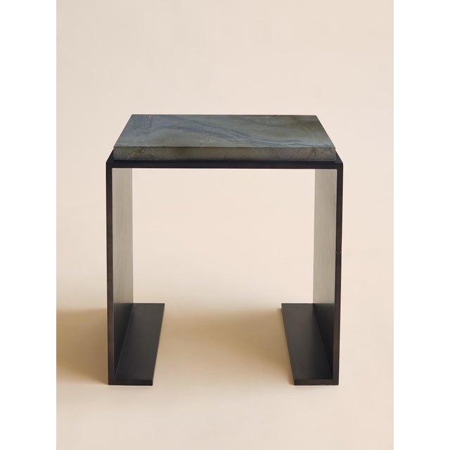 This sculptural side table pairs a clean, architectural steel base with a solid marble top, creating a striking balance of...