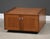 A mid century modern teak square coffee table with two doors, chrome finger pulls and an open bookshelf in the back side....