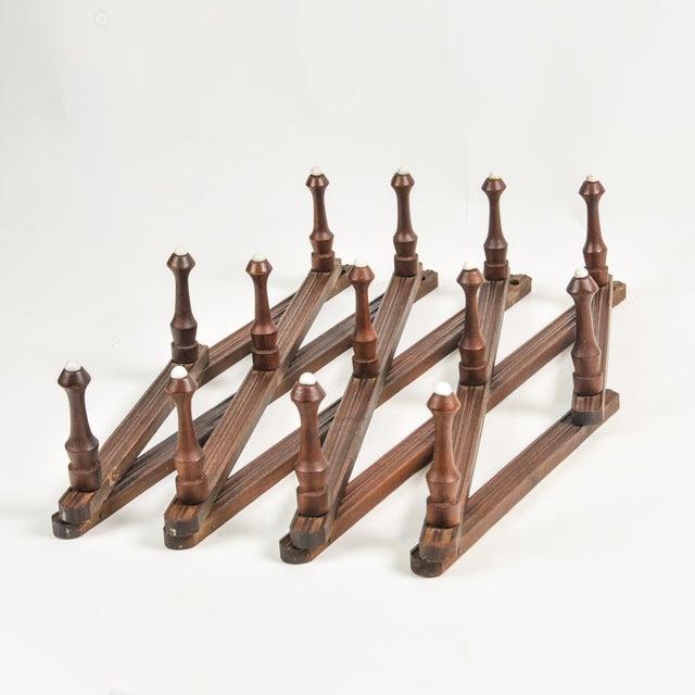 Beautiful, expertly crafted, dark wood antique accordion peg rack. Each peg is tipped with a white glass or porcelain...