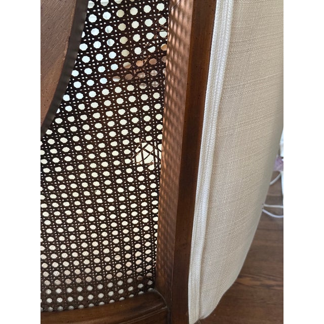 Elegant vintage cane-back settee featuring a warm walnut-toned wood frame, curved arms, and finely woven cane side panels....