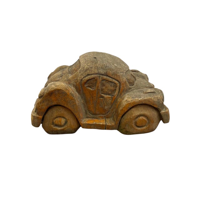 Large-scale vintage hand carved wooden sculpture depicting a stylized automobile, reminiscent of a classic Volkswagen...