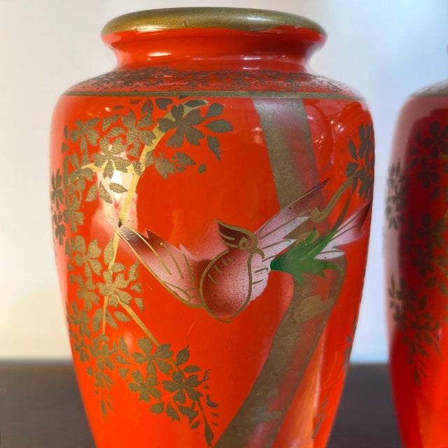Pair of orange-red oriental ceramic vases. The handmade decorations depict a bird of paradise and in the background a...