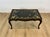 A stylish Chinoiserie decorated gilt wood and ebonized coffee table with an inset glass and scalloped top, painted apron,...
