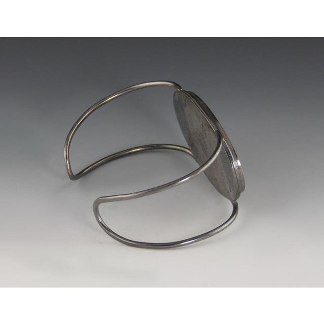 This hand fabricated bangle by American artist Sadie Wang, features stylized leaves crafted in sterling silver, and filled...