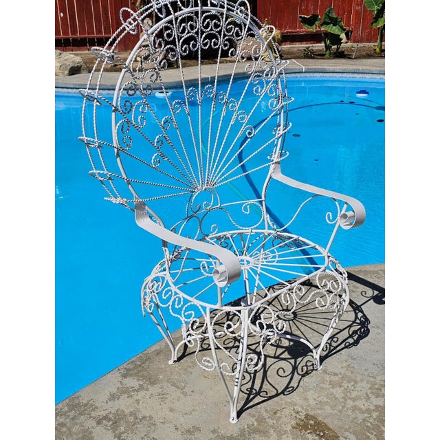 This monumental vintage wrought iron peacock chair, in the Salterini style, features an exaggerated fan back with...