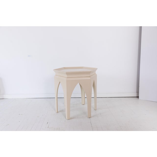 A Madcap Cottage Baker Furniture six-sided, white-painted Moroccan-style side table with arched legs and hexagonal rimmed...
