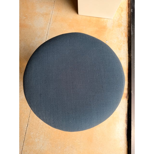 Contemporary round ottoman upholstered in a rich navy textured fabric for a refined, versatile look. Its clean, tailored...