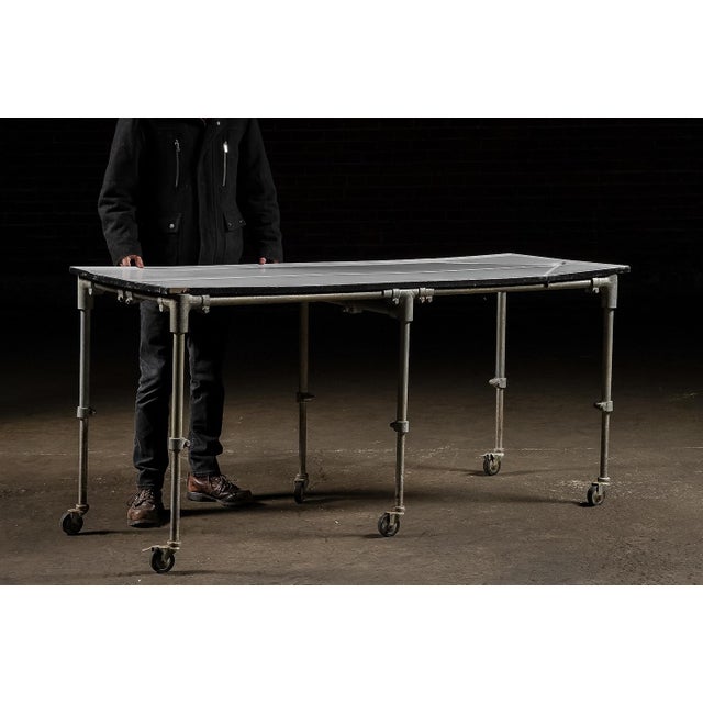 Heavy-duty embalming or preparation table featuring a porcelain enamel steel top set within a blackened steel perimeter...