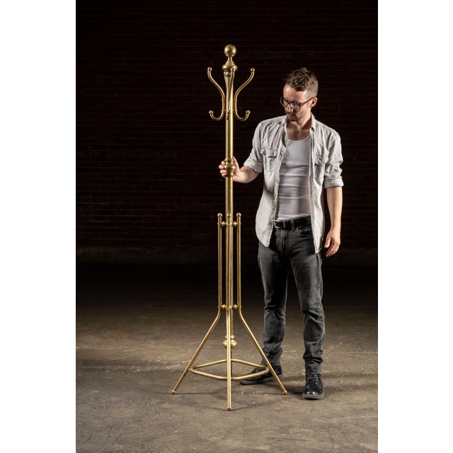 Early 20th century brass coat tree. This freestanding coat stand features a polished brass finish with elegant turned...