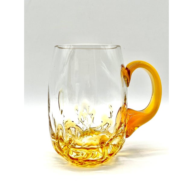 A decorative, mouth-blown pitcher featuring clear and amber accents. The chipped edge on the base is a testament to...