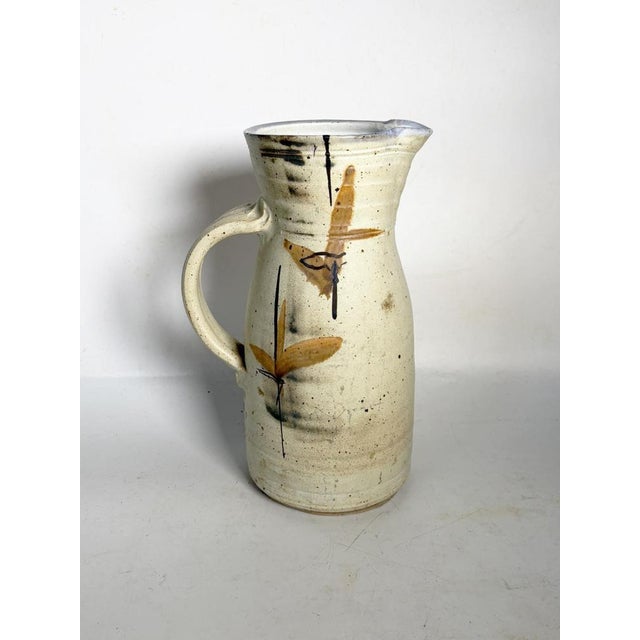 A white and brown glazed ceramic vase, made in France, dating from the late 1950s/early 1960s. Its slender shape with a...