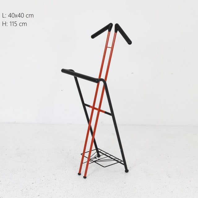 Valet stand or valet stand in red painted metal and black plastic. Made in Italy in the 1970s. Foldable.
