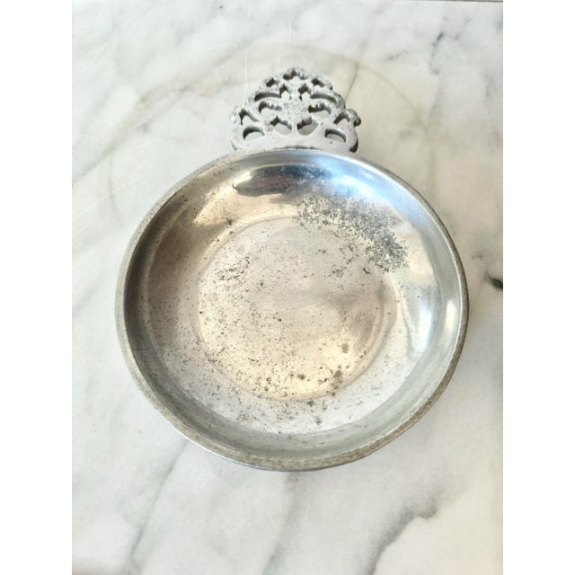 This vintage silver-toned ashtray features a delicately ornate handle, adding a touch of elegance to any setting. With its...