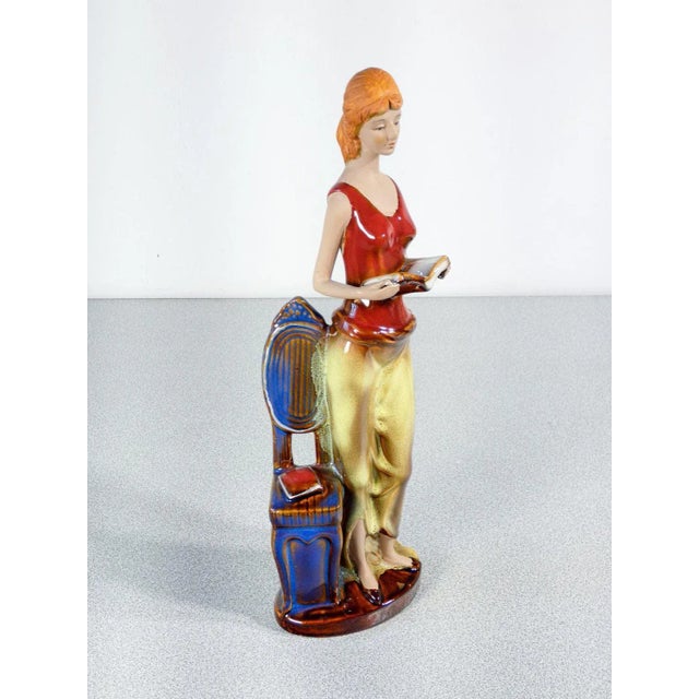 Painted and glazed ceramic sculpture woman with books. Origin italy period twentieth century materials painted and glazed...